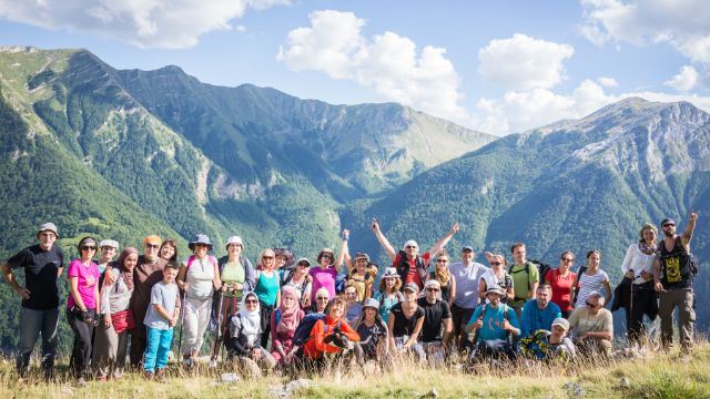 A group of people posing for a photo in front of a mountain.