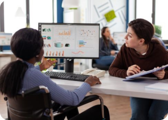 A few people sitting at a table looking at a computer screen.