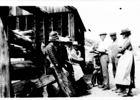 A group of people standing outside a hut.
