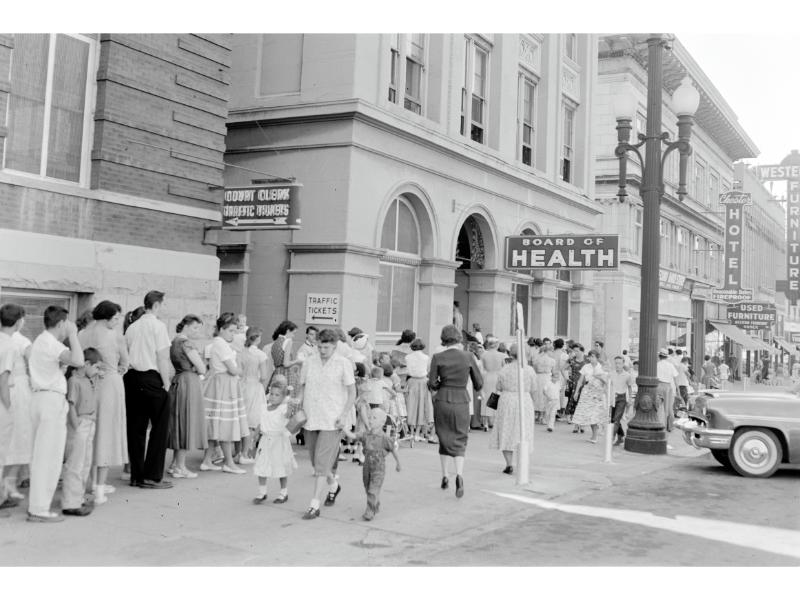 A crowd of people standing on the sidewalk.