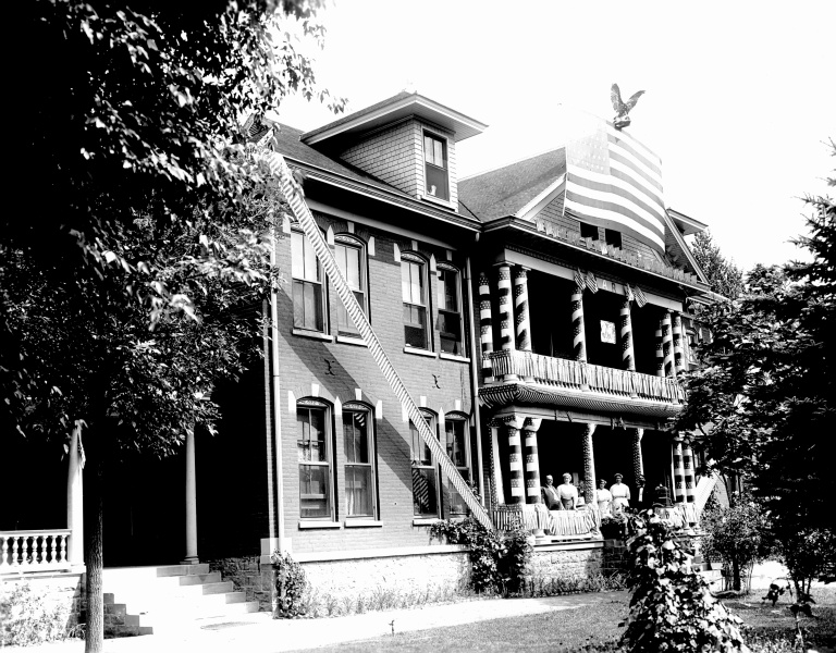 A large house with a few people sitting on the porch.