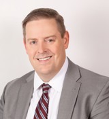 A man in a suit smiling.