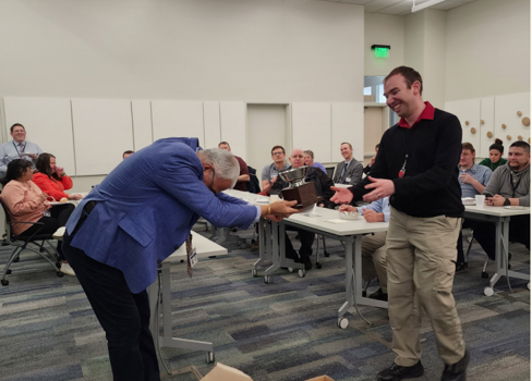 A person handing another man something on the laptop.