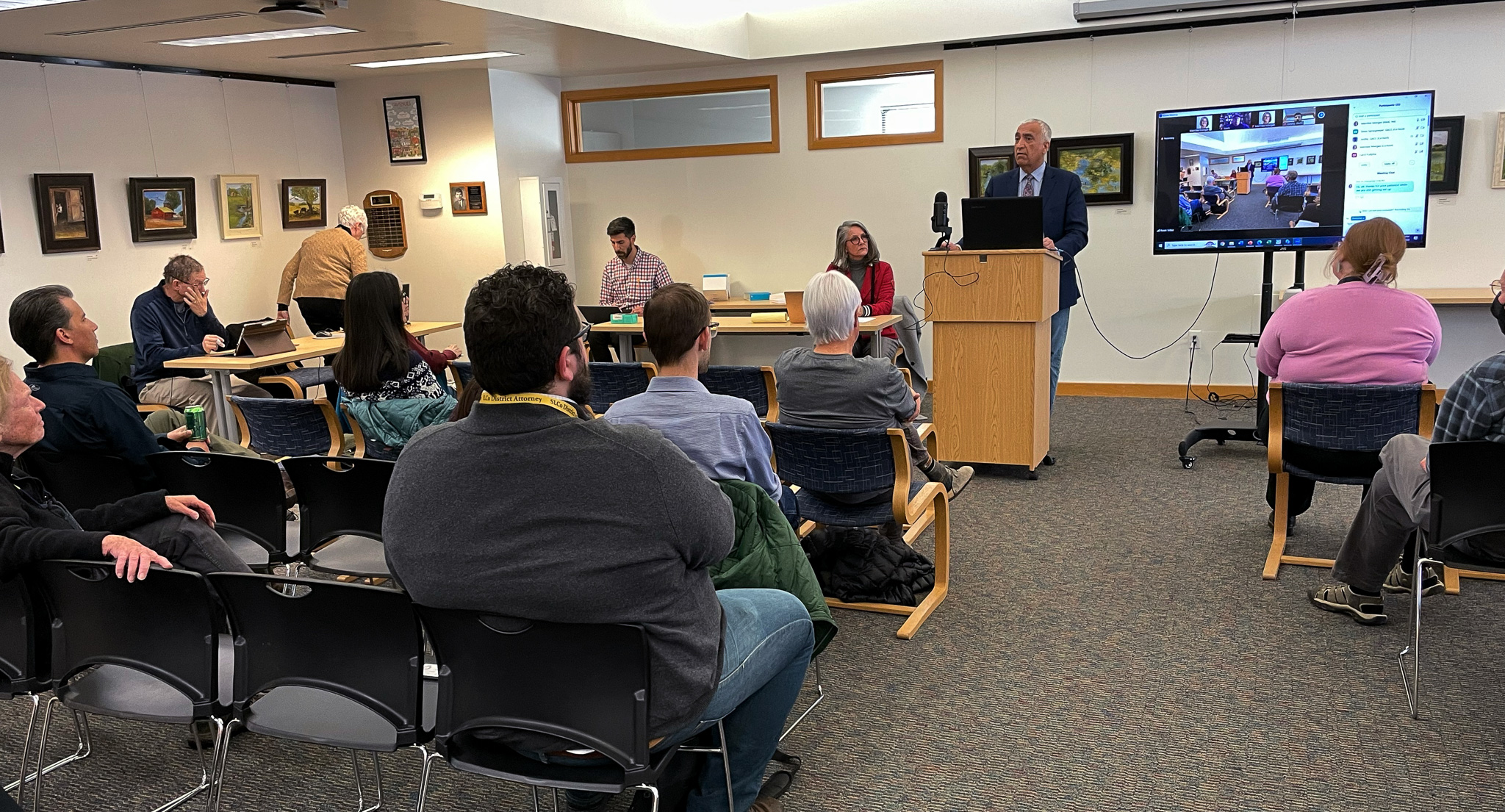 A group of people sitting in a room with a person standing in front of a screen.
