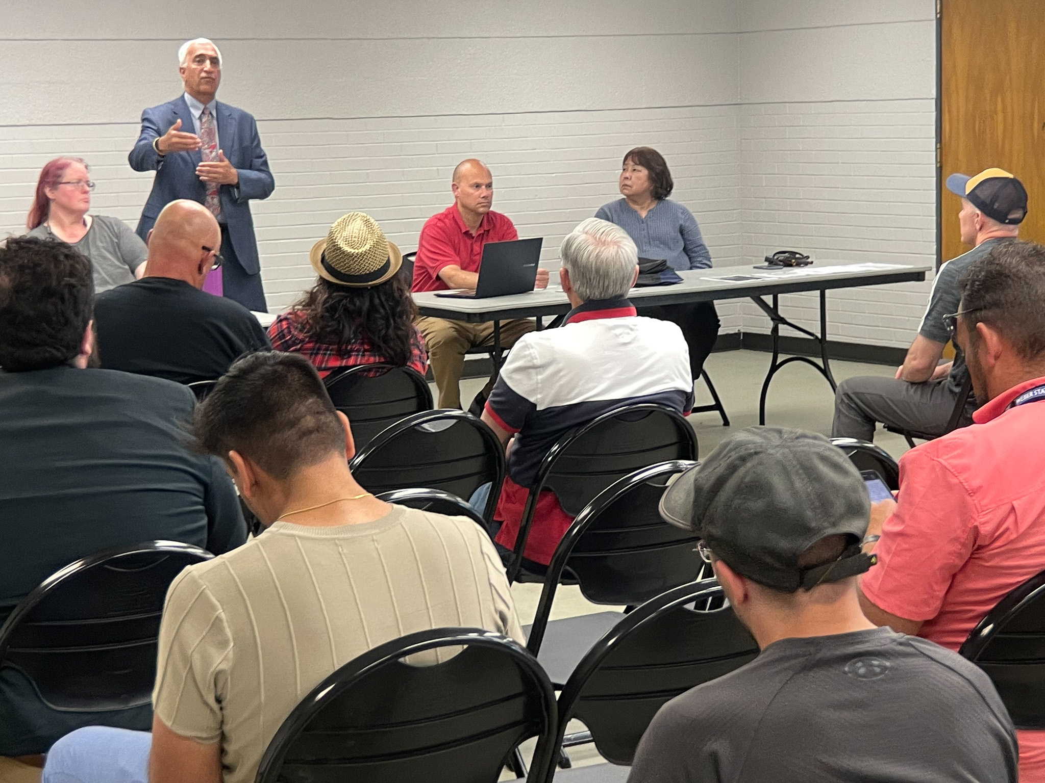 A man standing in front of a group of people sitting at tables.