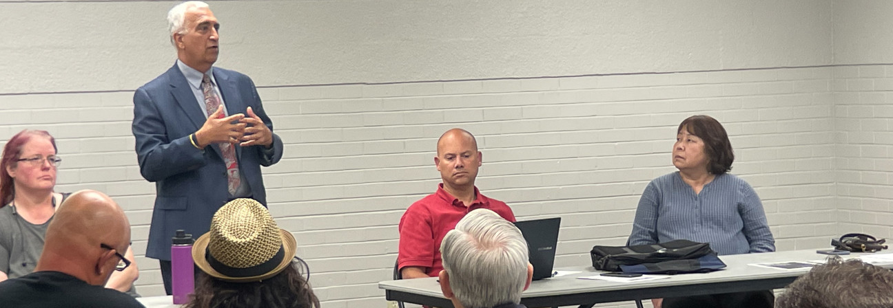 A man speaking to a group of people sitting at tables.