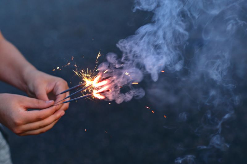 A hand holding a stick with fire.
