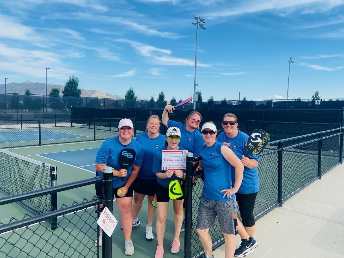 A group of people posing for a photo with a tennis racket.