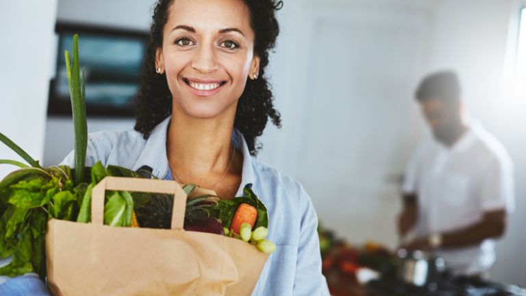 A woman holding a bag of vegetables.