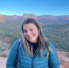 A woman smiling with a canyon in the background.