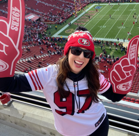 A person wearing a red hat and sunglasses in a stadium.