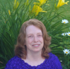 A person smiling in front of a bush of flowers.