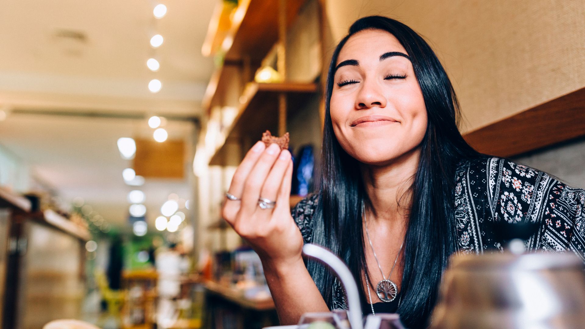 A woman smiling and holding a piece of food.