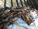 A pile of wood next to a water fall.