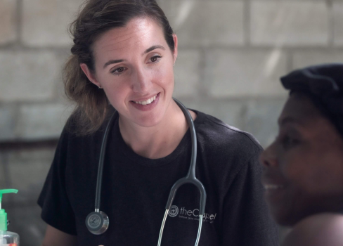 A woman smiling with a man behind her.