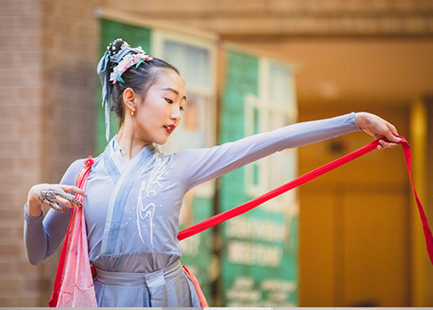 A girl holding a red and white ribbon.