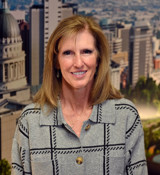 A woman smiling with a city in the background.