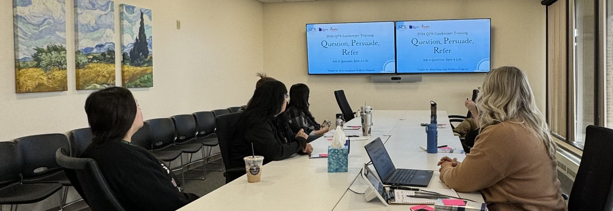 A group of people sitting around a table looking at a screen.