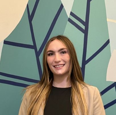 A person smiling in front of a wall with a blue and yellow background.