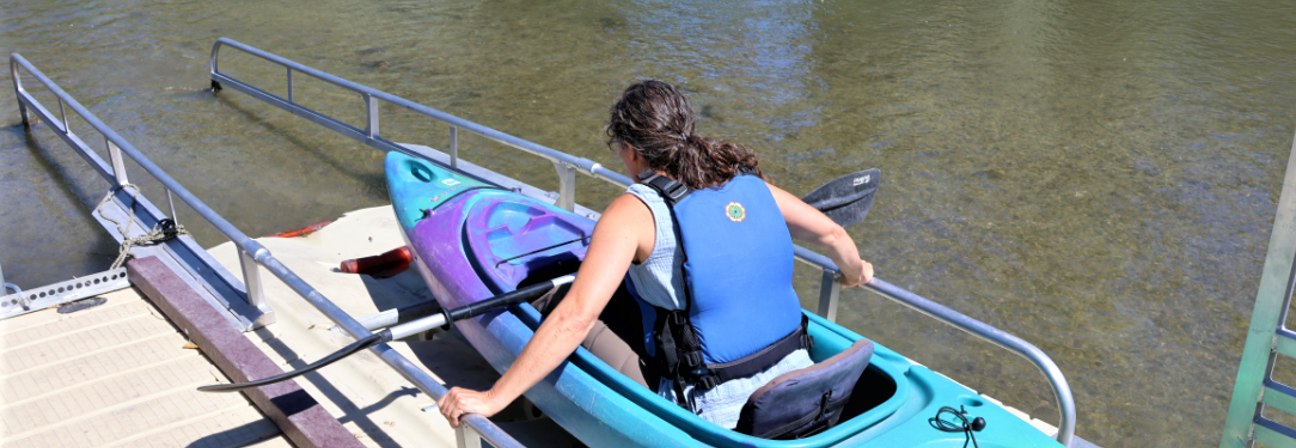 A girl in a kayak on a dock.