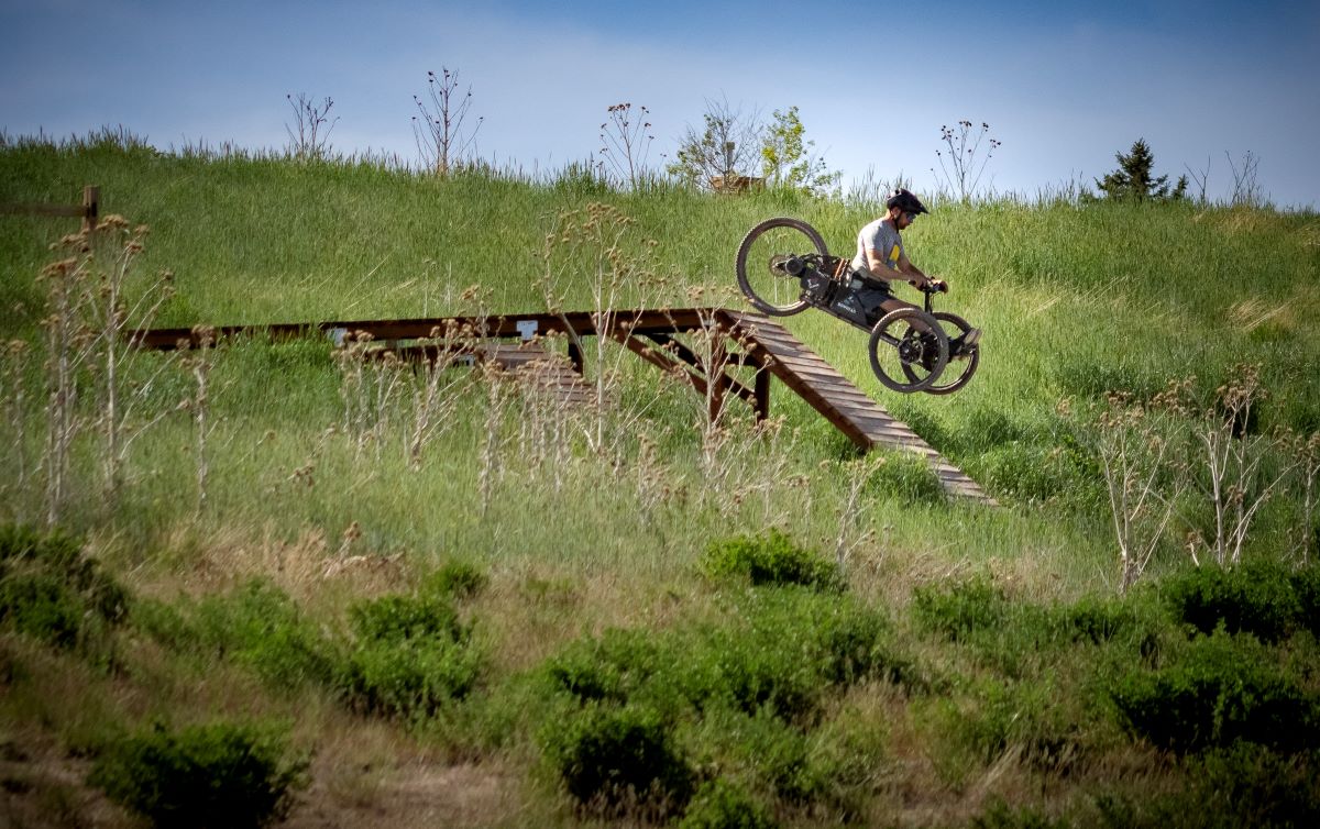 A person riding a bike on a wooden bridge in a field.