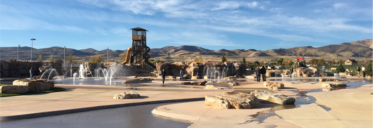 A group of people standing around a fountain in a large open area.